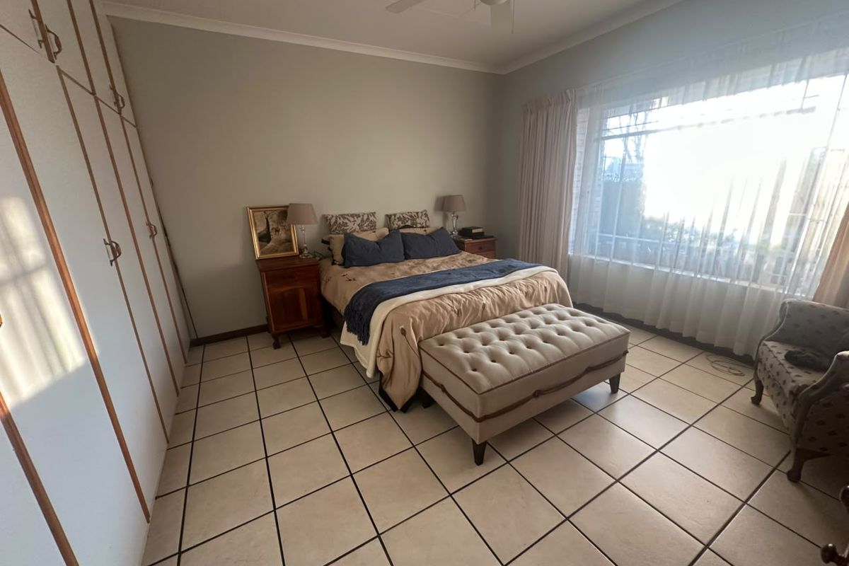 Spacious bedroom featuring large built-in wardrobes, tiled flooring, and a ceiling fan, offering a functional and well-lit living space.