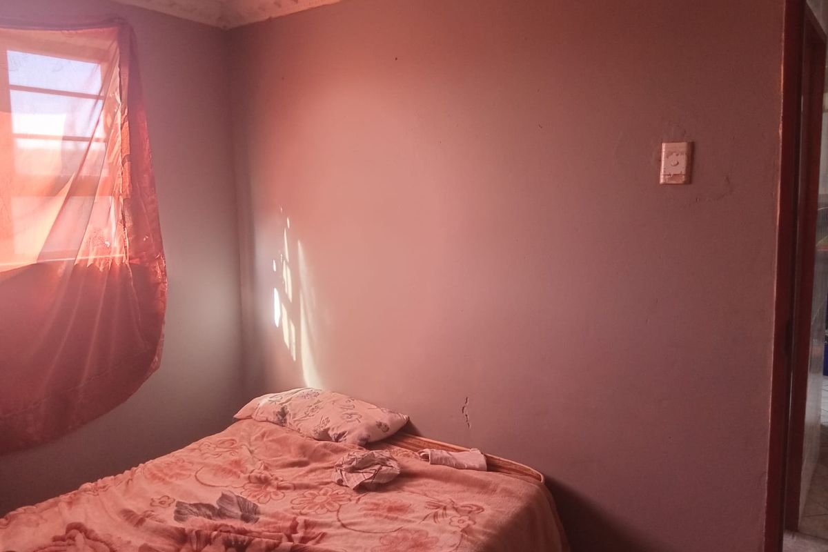 A bedroom featuring decorative ceiling cornicing and a wall with visible plaster cracking, requiring maintenance and cosmetic updates.