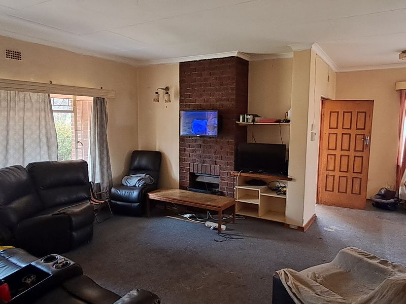 Spacious living room featuring a central brick fireplace, large windows for natural light, and traditional timber door access.