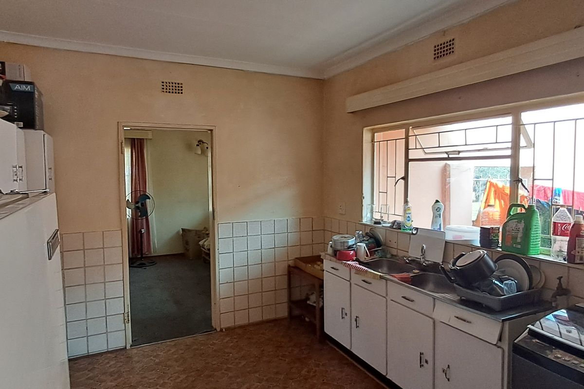 A dated kitchen featuring original cabinetry, a double basin sink, and tiled splashbacks, offering significant potential for a modern renovation.