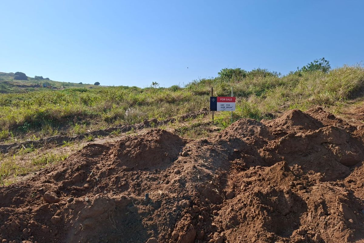 A view of a vacant residential plot of land featuring natural vegetation and a for sale sign.