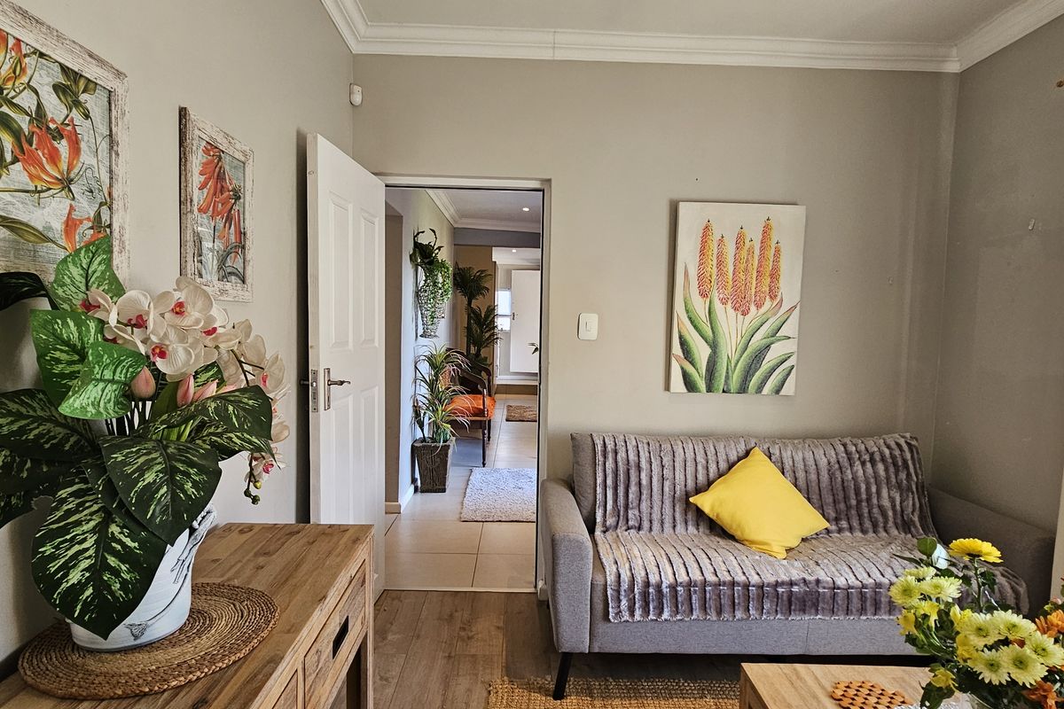 A cozy living room featuring crown molding, tiled flooring, and a doorway leading to an adjacent space.