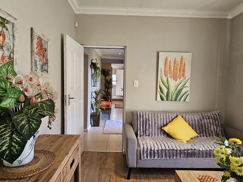 A cozy living room featuring crown molding, tiled flooring, and a doorway leading to an adjacent space.