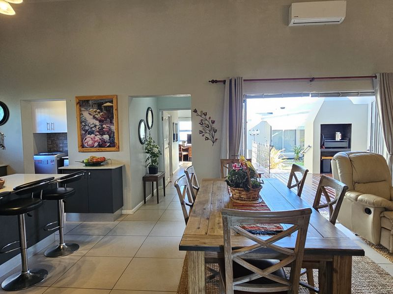 Spacious open-plan living area featuring a modern kitchen with island seating, tiled floors, and seamless flow to an outdoor patio through sliding glass doors.