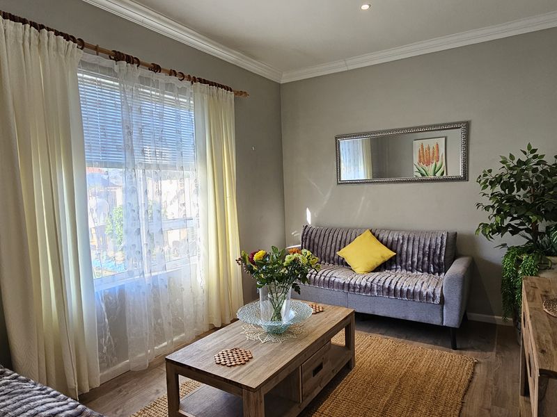 A well-maintained living room featuring laminate flooring, crown molding, and recessed downlights, offering a comfortable and inviting atmosphere.