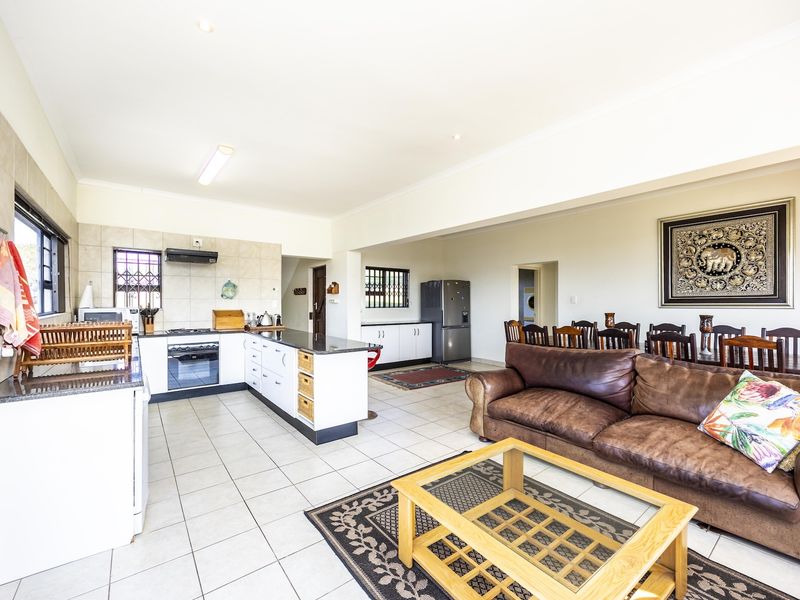 Spacious open-plan living and kitchen area featuring tiled flooring, modern cabinetry, and integrated kitchen appliances, creating a functional and connected family space.