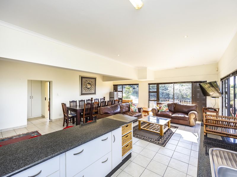 Spacious open-plan living and dining area featuring tiled floors, modern kitchen cabinetry with granite countertops, and large sliding doors leading to an outdoor space.