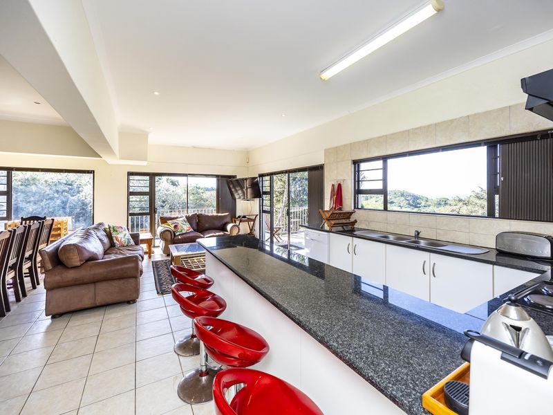 Spacious open-plan kitchen and living area featuring granite countertops, tiled flooring, and large sliding doors leading to an outdoor balcony with scenic views.