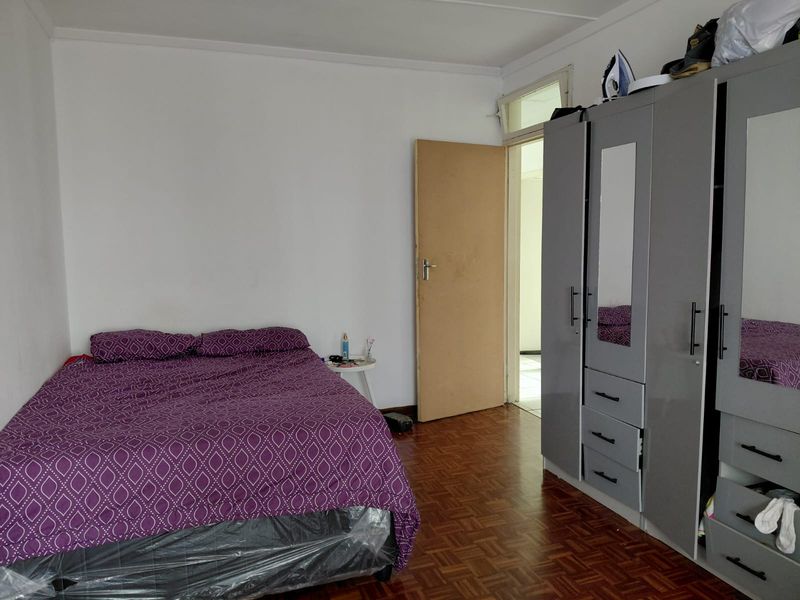 A bedroom featuring parquet flooring and a built-in wardrobe with mirrored panels.