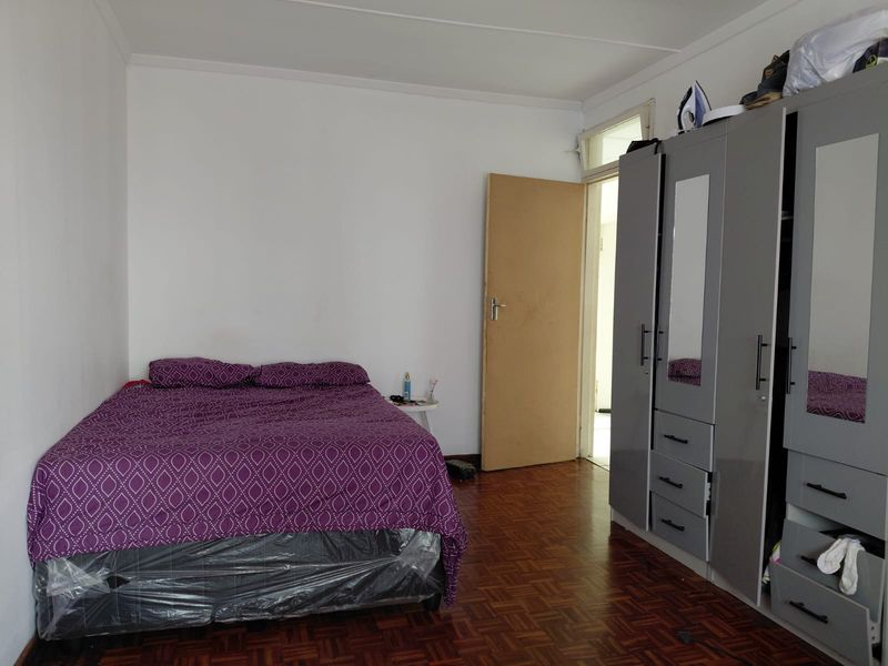 A bedroom featuring parquet flooring and a built-in wardrobe with mirrored panels.