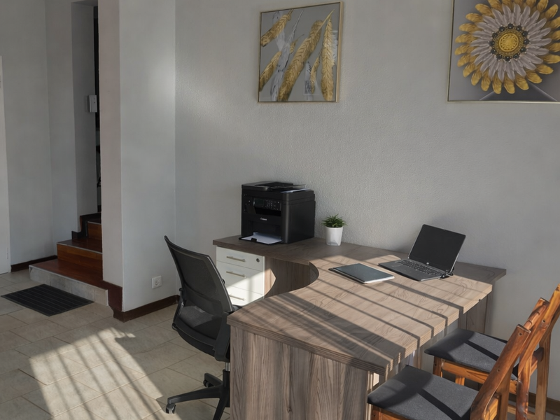 A functional home office space featuring tiled flooring and direct access to an internal staircase.