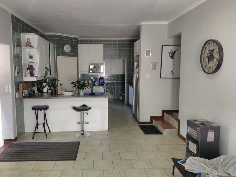 Open plan kitchen and living area featuring a breakfast bar, tiled flooring, and built-in cabinetry with a tiled backsplash.