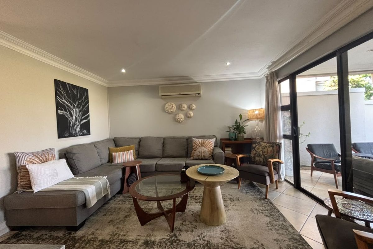 A comfortable living room featuring tiled floors, recessed lighting, and large sliding glass doors that provide seamless access to the outdoor patio area.