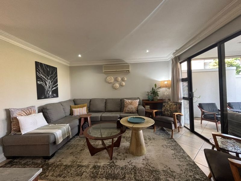 A comfortable living room featuring tiled floors, recessed lighting, and large sliding glass doors that provide seamless access to the outdoor patio area.