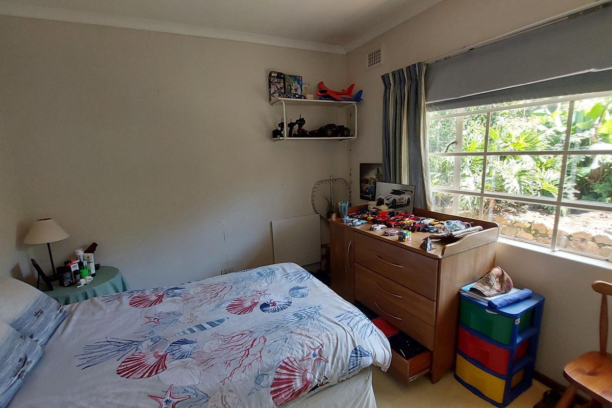 A standard bedroom featuring a large window with garden views, neutral wall finishes, and a functional layout suitable for a child or guest room.