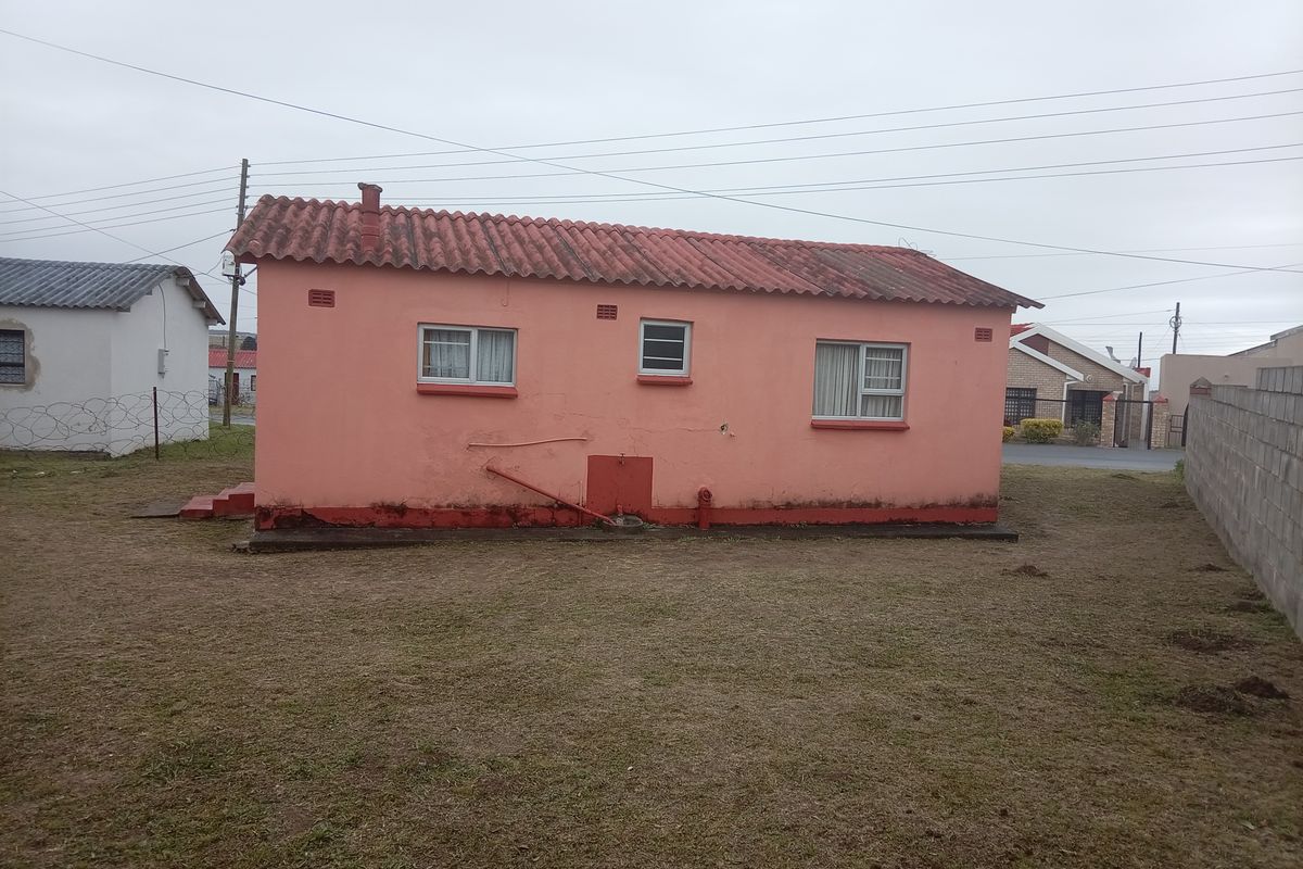 Rear view of a detached house featuring a tiled roof, sliding windows, and visible exterior wall maintenance requirements.