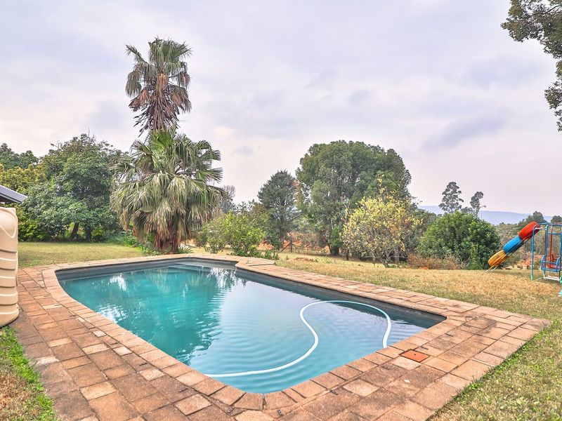 Outdoor pool area featuring a swimming pool with brick coping, a water storage tank, and a spacious garden setting.