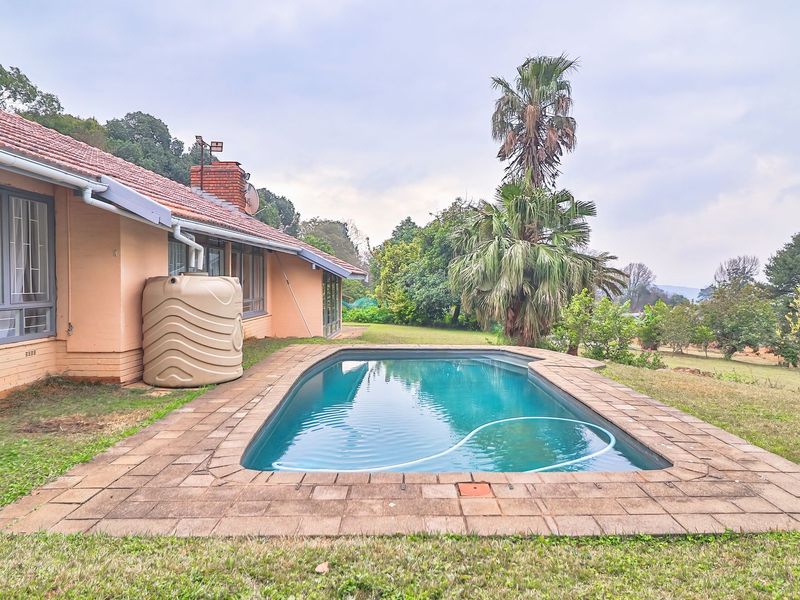 Outdoor pool area featuring a paved surround, water storage tank, and direct access to the rear of the house with a tiled roof.