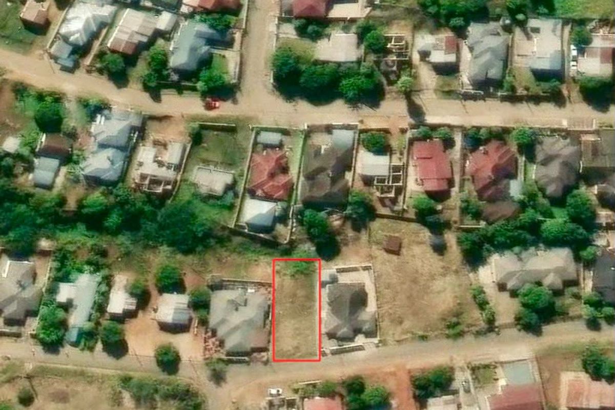 An aerial view of a vacant residential land plot situated within an established suburban neighborhood.
