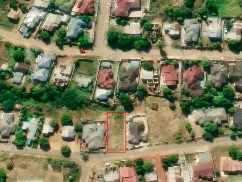 An aerial view of a vacant residential land plot situated within an established suburban neighborhood.
