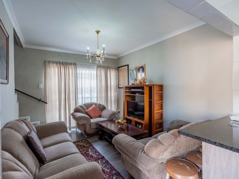 Open plan living area featuring laminate flooring, a breakfast bar, and direct access to the exterior through a security gate.