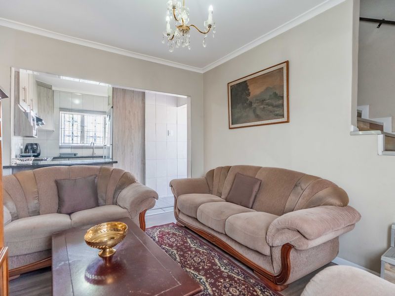 A comfortable living room featuring a staircase and an open pass-through window connecting to the kitchen area.