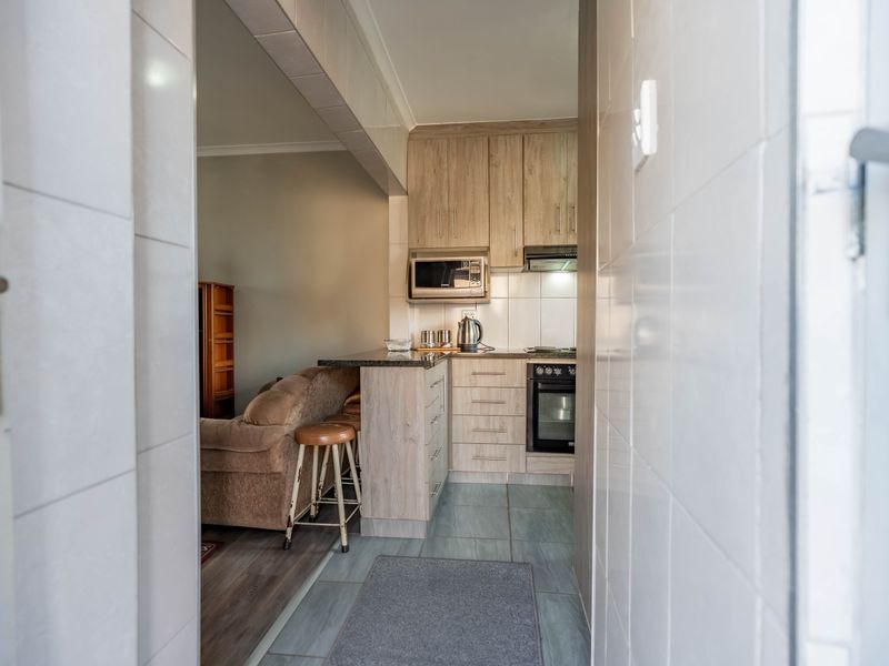 A compact, functional kitchen featuring light wood-finish cabinetry, granite countertops, built-in oven, and an integrated microwave, seamlessly flowing into the adjacent living area.