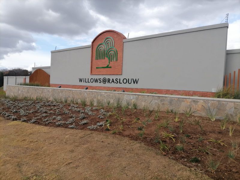 The entrance facade of Willows@Raslouw featuring a modern perimeter wall, stone cladding, and professional signage with integrated electric fencing.