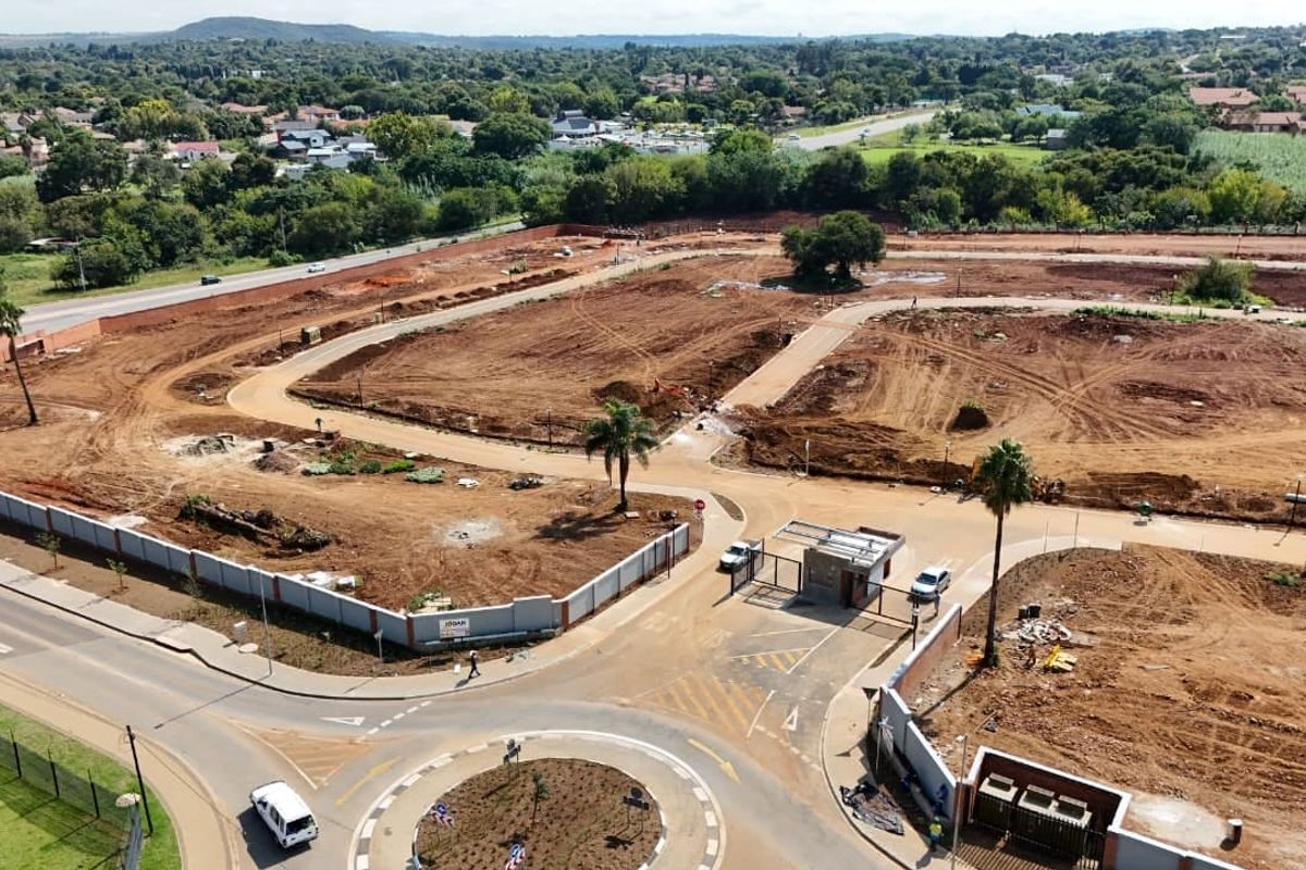 Aerial view of a residential development site showing cleared land, internal road infrastructure, and a secure gated entrance.