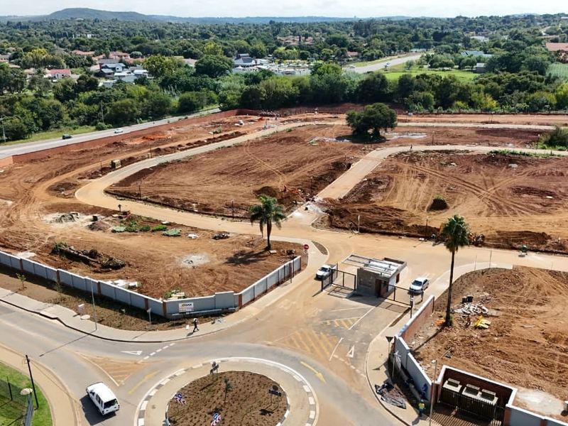 Aerial view of a residential development site showing cleared land, internal road infrastructure, and a secure gated entrance.