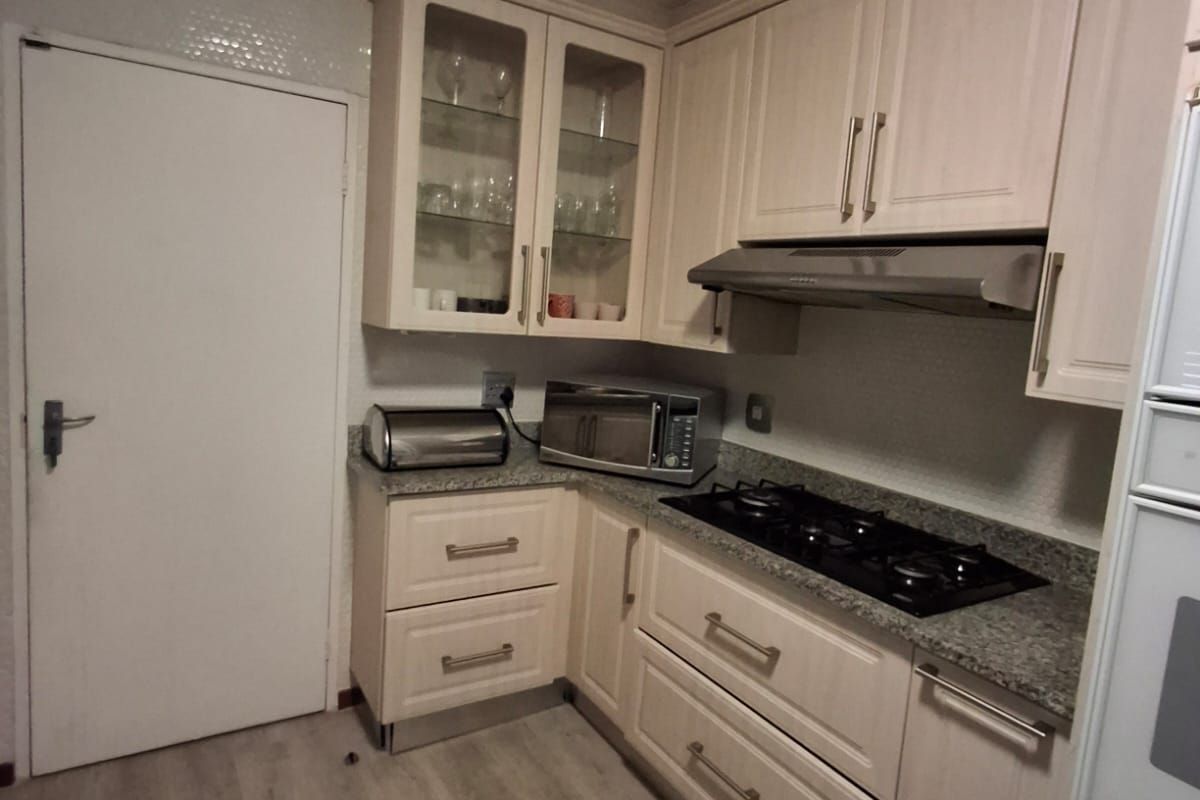 A functional kitchen featuring light-toned cabinetry, granite countertops, a gas hob with extractor fan, and integrated oven, offering a clean and practical workspace.