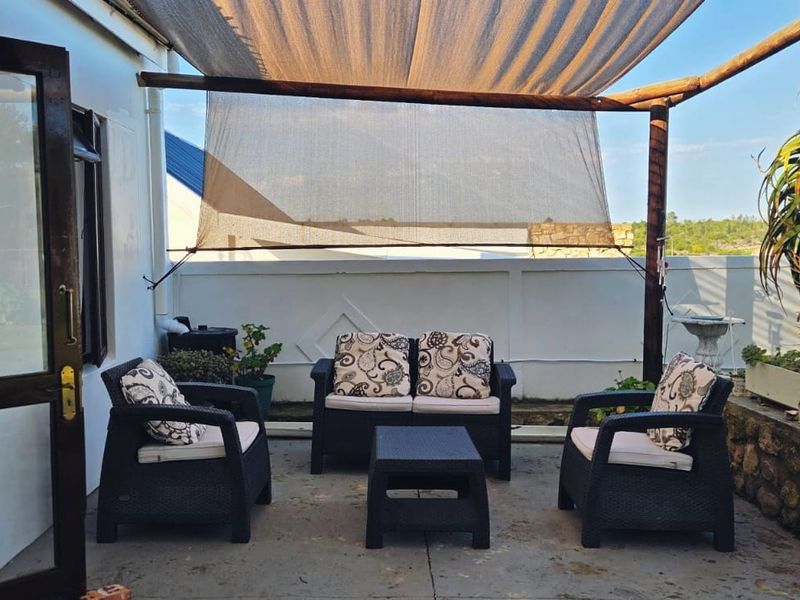 Outdoor patio area featuring a timber pergola with shade cloth, concrete paving, and a stone retaining wall.