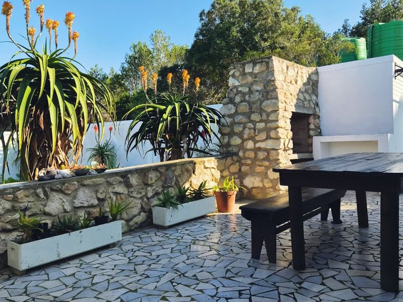 Outdoor patio area featuring a stone-clad built-in braai, masonry counter, and durable crazy paving flooring, ideal for alfresco dining and entertaining.