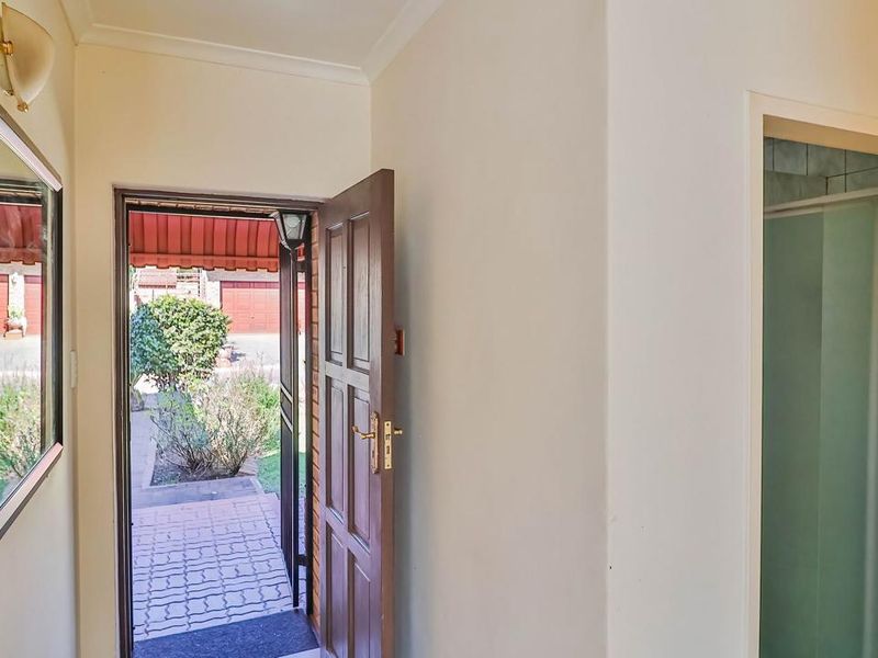 A bright entrance hall featuring a timber front door leading to an outdoor paved area, with neutral walls and coving.