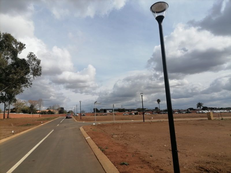 A view of the paved street and infrastructure within a residential vacant land development, featuring established street lighting and clear access.