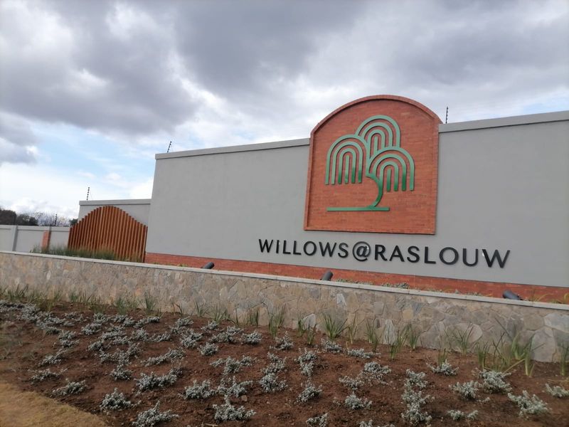 Entrance signage and boundary wall for the Willows at Raslouw residential estate, featuring stone cladding and integrated security fencing.