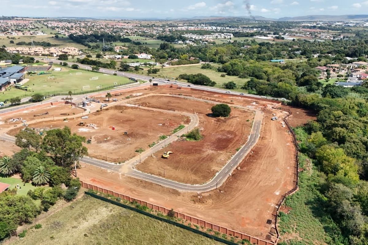 Aerial view of a residential development site showing cleared land, internal road infrastructure, and perimeter fencing in a suburban setting.