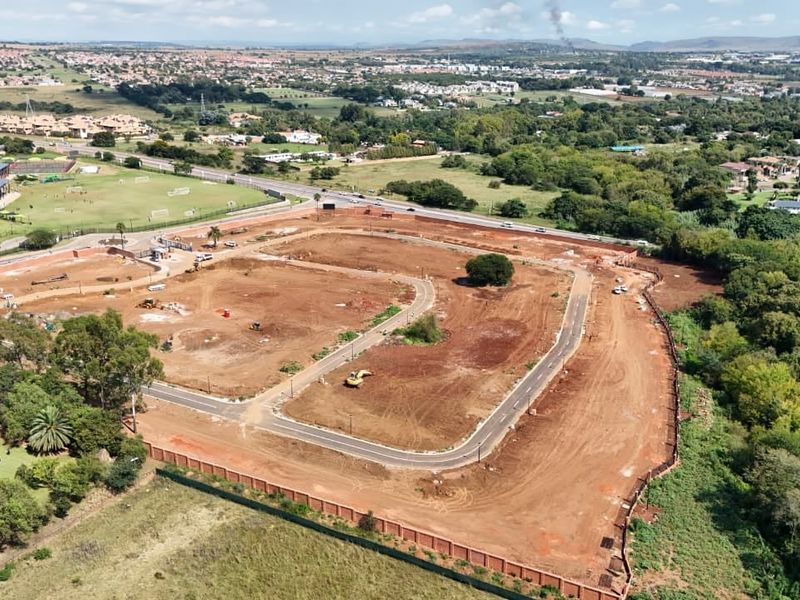 Aerial view of a residential development site showing cleared land, internal road infrastructure, and perimeter fencing in a suburban setting.