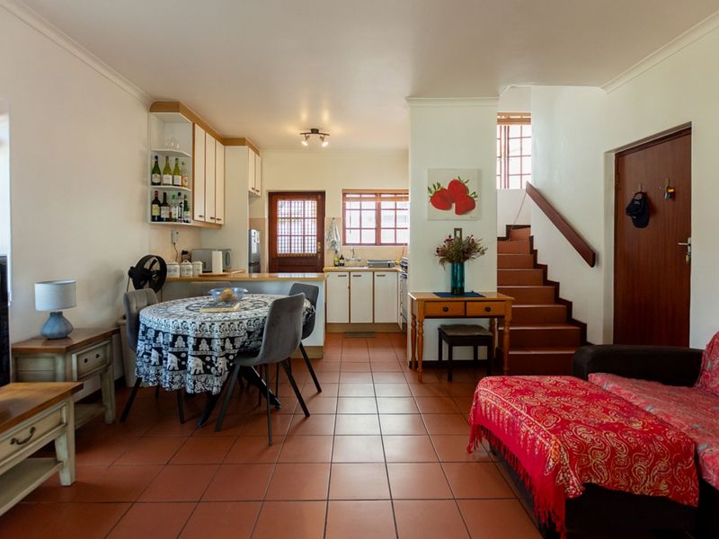 Open-plan living and kitchen area featuring tiled flooring, built-in cabinetry, and a staircase leading to the upper level.