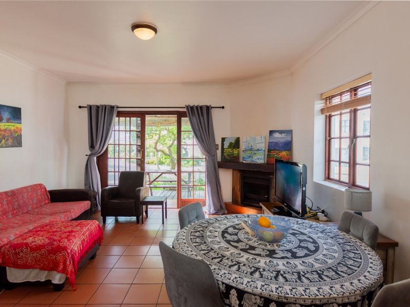 Open plan living and dining area featuring tiled floors, a fireplace, and direct access to an outdoor patio through wooden framed glass sliding doors.