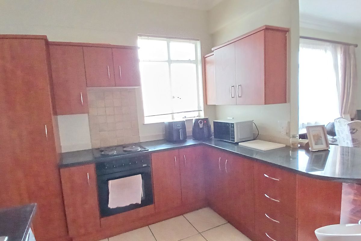 Functional kitchen featuring laminate cabinetry, granite countertops, built-in oven, electric hob, and tiled flooring, offering a practical layout for daily cooking.