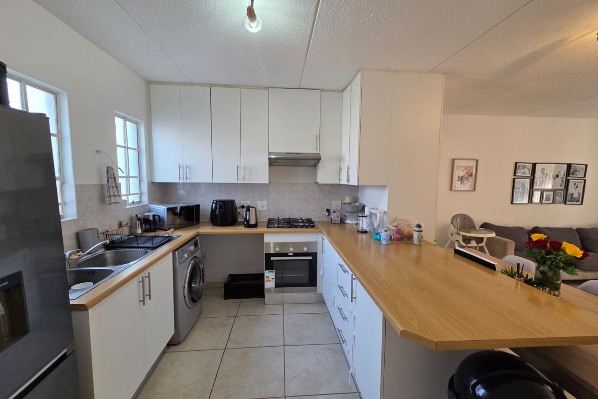 Functional kitchen featuring white cabinetry, wooden countertops, a breakfast bar, gas hob, built-in oven, and tiled flooring, seamlessly integrated with the living area.