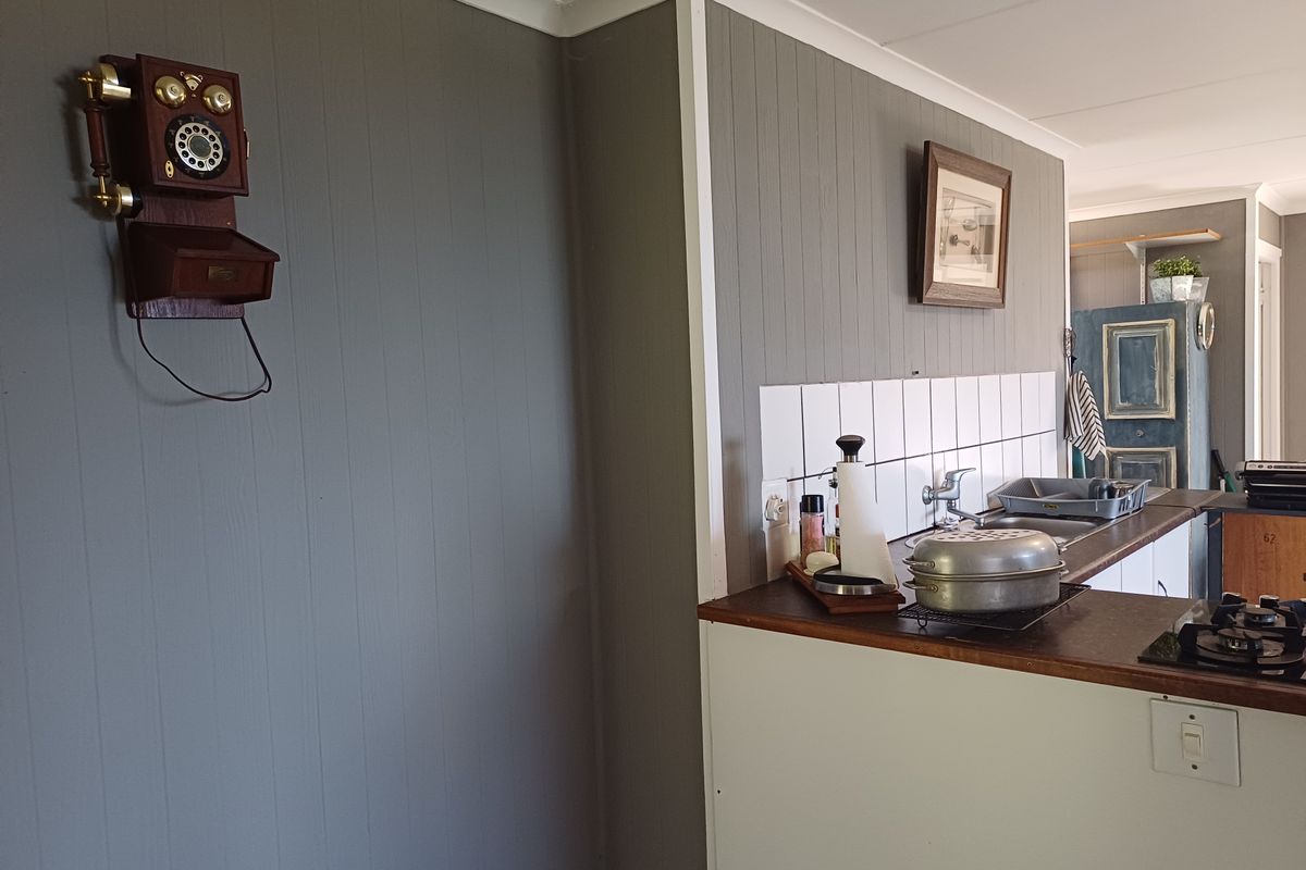 A kitchen area featuring timber wall paneling, a tiled splashback, laminate countertops, and a built-in gas hob.
