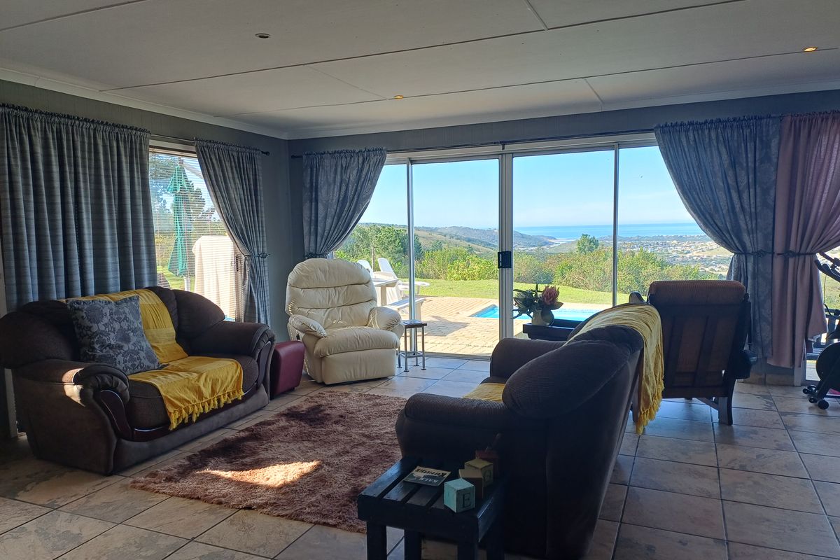 Spacious living room featuring tiled floors and large sliding glass doors that open to a patio with scenic coastal and pool views.