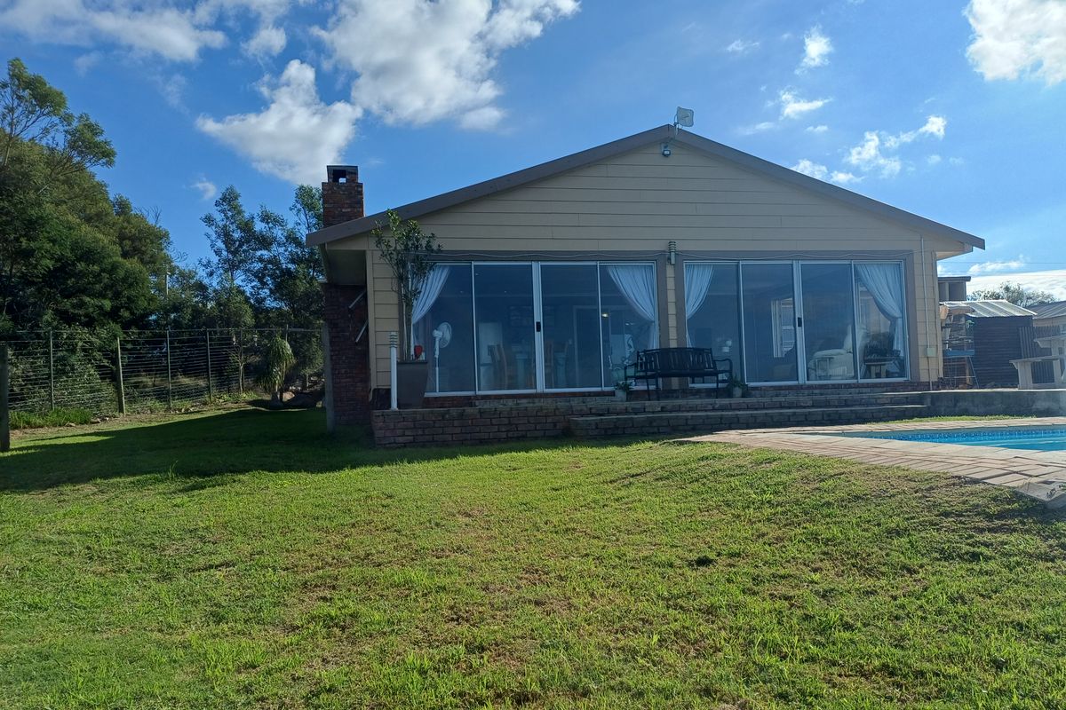 Rear view of the house featuring a brick chimney, large sliding glass doors leading to a patio, and an adjacent swimming pool.
