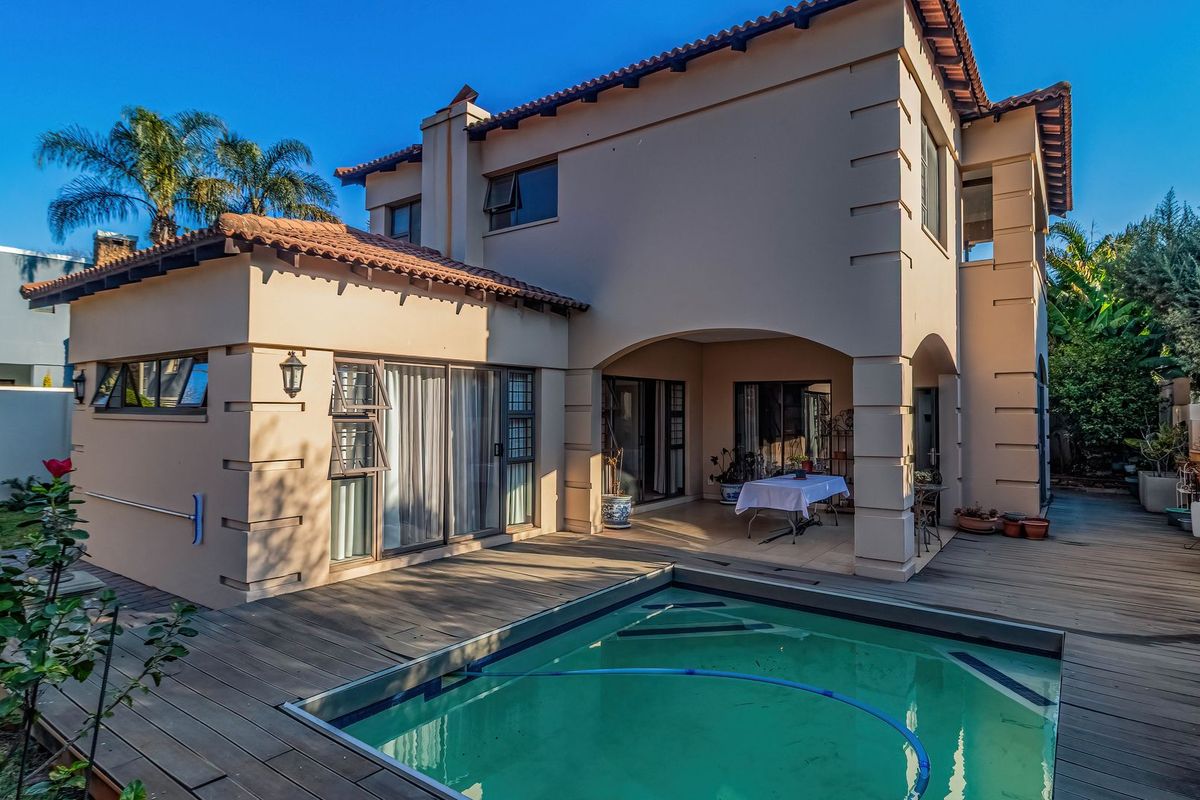 Rear view of the property featuring a swimming pool, timber decking, and a covered patio area with access to the main living space.