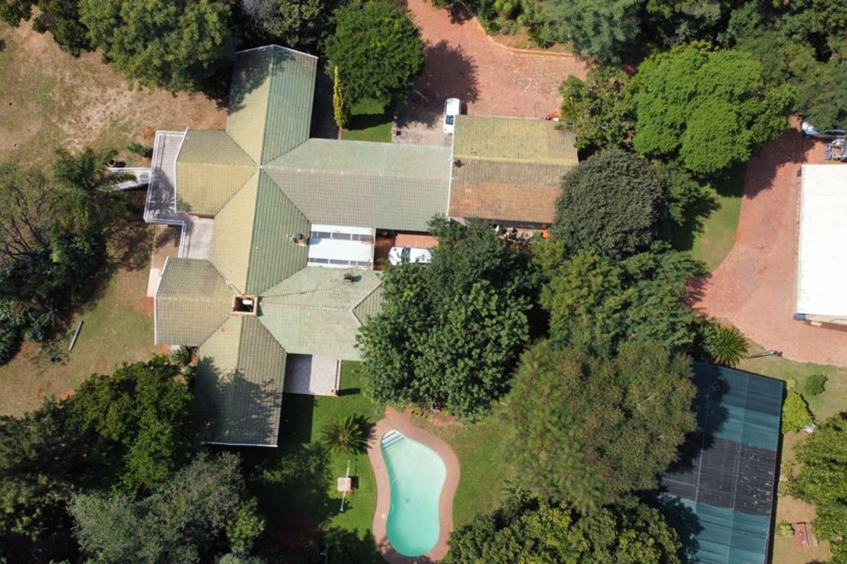 Aerial view of a small holding property featuring a main residence with a tiled roof, a swimming pool, and a separate outbuilding on a large plot.