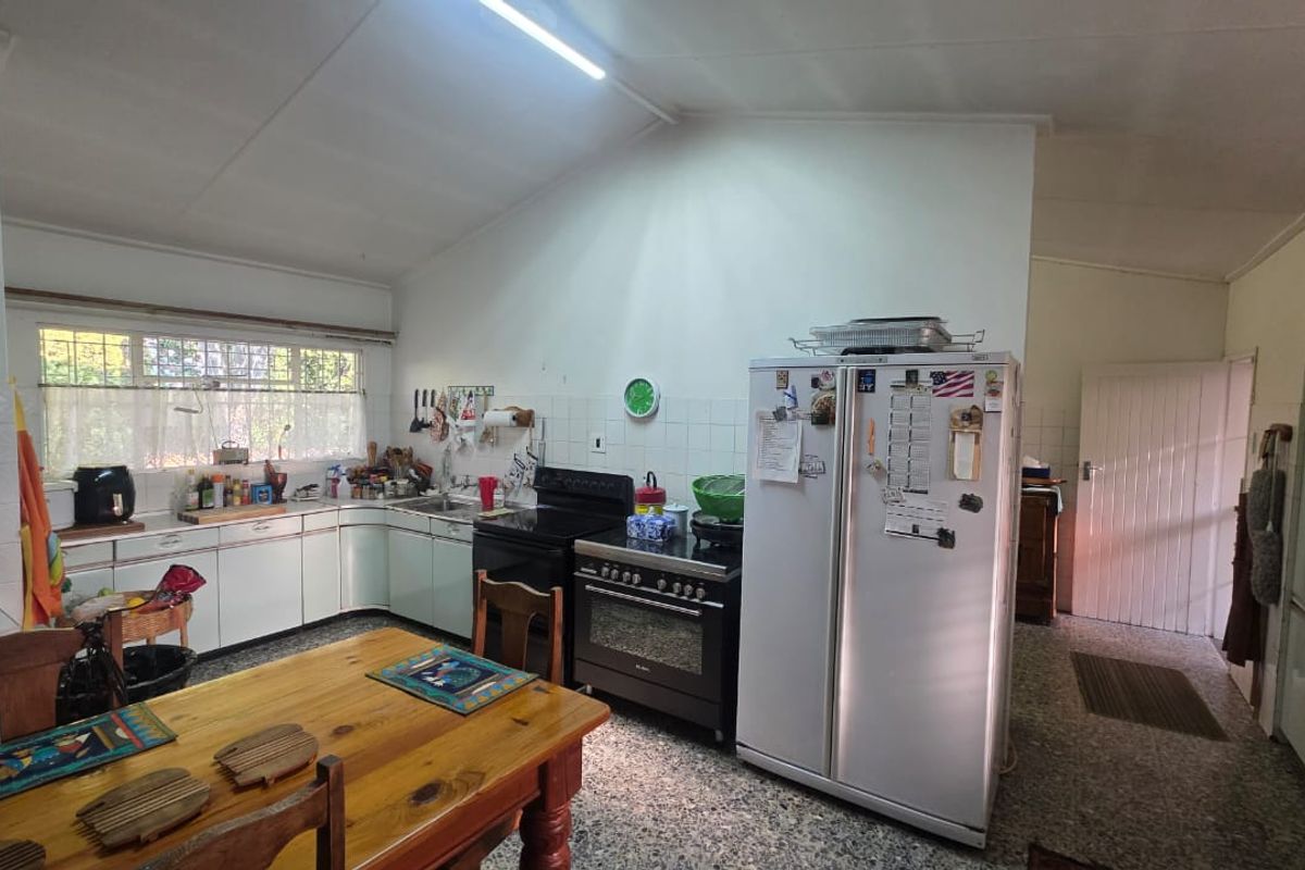 A functional kitchen featuring built-in cabinetry, a double sink, and a freestanding oven, with a vaulted ceiling and tiled splashback.