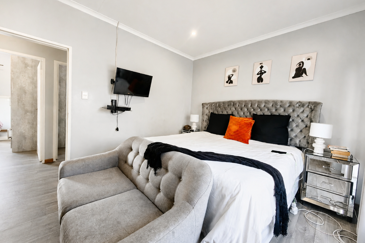 A well-maintained bedroom featuring neutral wall tones, coving, and modern laminate flooring, providing a clean and comfortable living space.