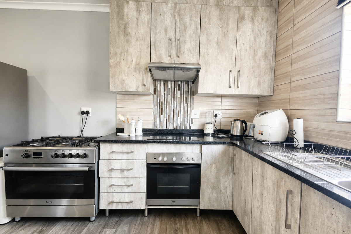 Modern kitchen featuring wood-look cabinetry, granite countertops, a gas hob, built-in oven, and a decorative tiled splashback.
